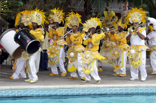A poolside band of Junkanoo performers dressed in yellow feathery costumes.